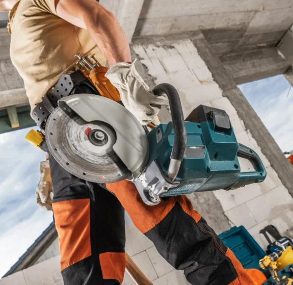 Arbetare med kapsåg utför betonghåltagning Stockholm på byggarbetsplats